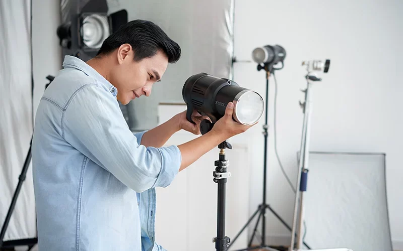 Person adjusting studio light in photography setup